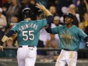 Seattle Mariners' James Jones, right, greets Michael Saunders at the plate after they both scored on a triple hit by Mariners' Brad Miller in the eighth inning of a baseball game against the Houston Astros, Monday, Sept. 8, 2014, in Seattle. (AP Photo/Ted S.