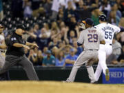 First base umpire Eric Cooper, left, calls Seattle Mariners' Michael Saunders safe at first base with a two-run single just ahead of Houston Astros relief pitcher Tony Sipp in the seventh inning Thursday.