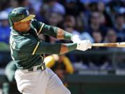 Oakland Athletics' Yoenis Cespedes hits a two-run home run against the Seattle Mariners in the eighth inning of a baseball game Sunday, April 13, 2014, in Seattle.