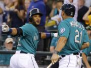 Seattle Mariners Robinson Cano, left, celebrates with Kendrys Morales, right, after Cano hit a solo home run in the first inning against the Oakland Athletics, Friday, Sept. 12, 2014, in Seattle. (AP Photo/Ted S.