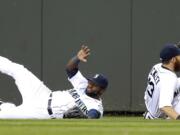 Seattle Mariners center fielder Abraham Almonte, left, slides in the outfield grass past center fielder Dustin Ackley, right, who caught but then dropped a fly ball hit by Oakland Athletics' Brandon Moss in the third inning of a baseball game on Saturday, April 12, 2014, in Seattle. (AP Photo/Ted S.