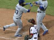 Diamondbacks' catcher Miguel Montero kneels as the Dodgers' Scott Van Slyke, left, is congratulated by teammate Adrian Gonzalez, right, after Van Slyke hit a two-run home run in the Major League Baseball opening game between the Los Angeles Dodgers and Arizona Diamondbacks at the Sydney Cricket Ground in Sydney, Australia Saturday, March 22, 2014.   The Dodgers won the game 3-1.