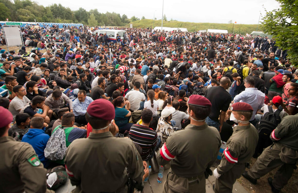 Migrants queue up for buses after they arrived at the border between Austria and Hungary near Heiligenkreuz, about 180 kms (110 miles) south of Vienna, Austria, Saturday, Sept. 19, 2015. Thousands of migrants who had been stuck for days in southeastern Europe started arriving in Austria early Saturday after Hungary escorted them to the border.