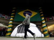 A man walks near a shopping center where a large Brazil flag and half of a soccer ball decorate the entrance in Sao Paulo, Brazil, Tuesday, June 10, 2014. The World Cup is set to open on June 12 with Brazil facing Croatia in Sao Paulo.