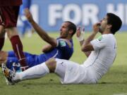 Uruguay's Luis Suarez holds his teeth after biting Italy's Giorgio Chiellini's shoulder during the group D World Cup soccer match between Italy and Uruguay at the Arena das Dunas in Natal, Brazil.