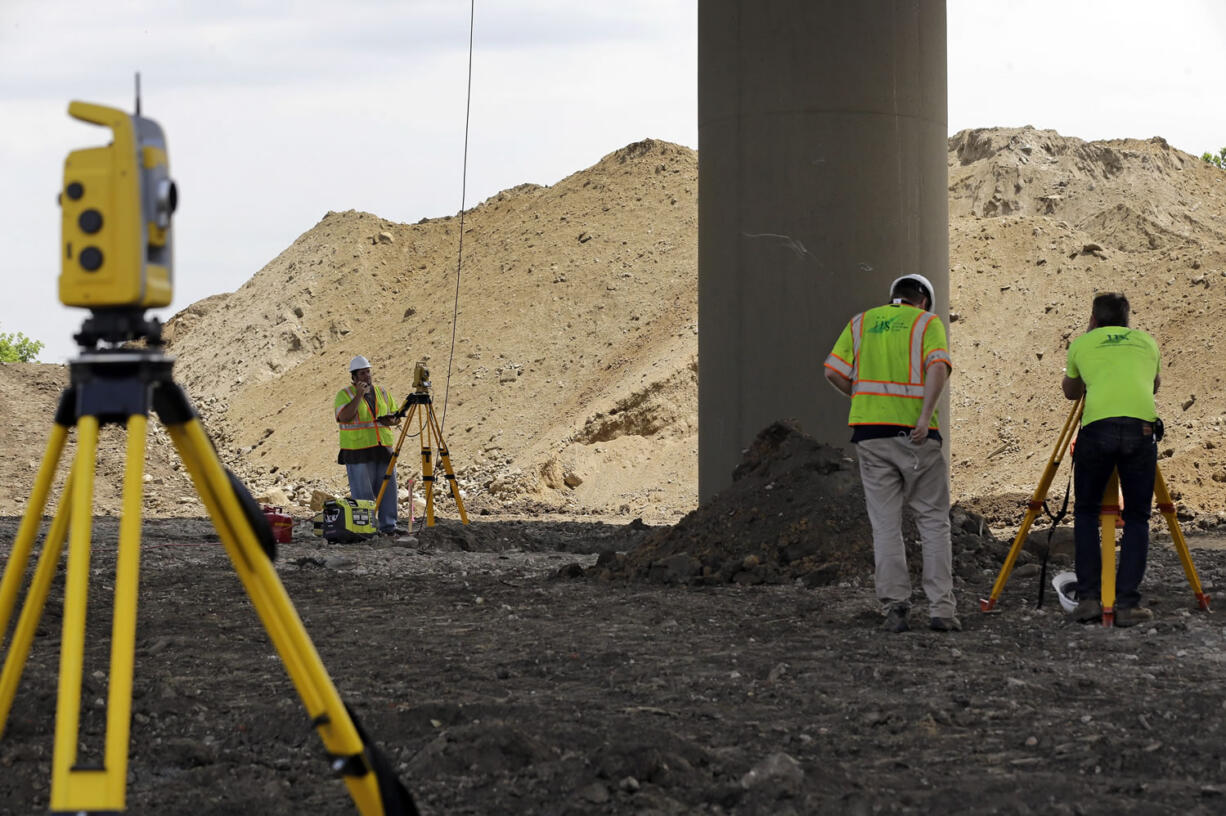 Surveyors stand near a tilting support column that is holding up the Interstate 495 bridge over the Christina River near Wilmington, Del., on Tuesday after it was closed due to the discovery of tilting support columns.