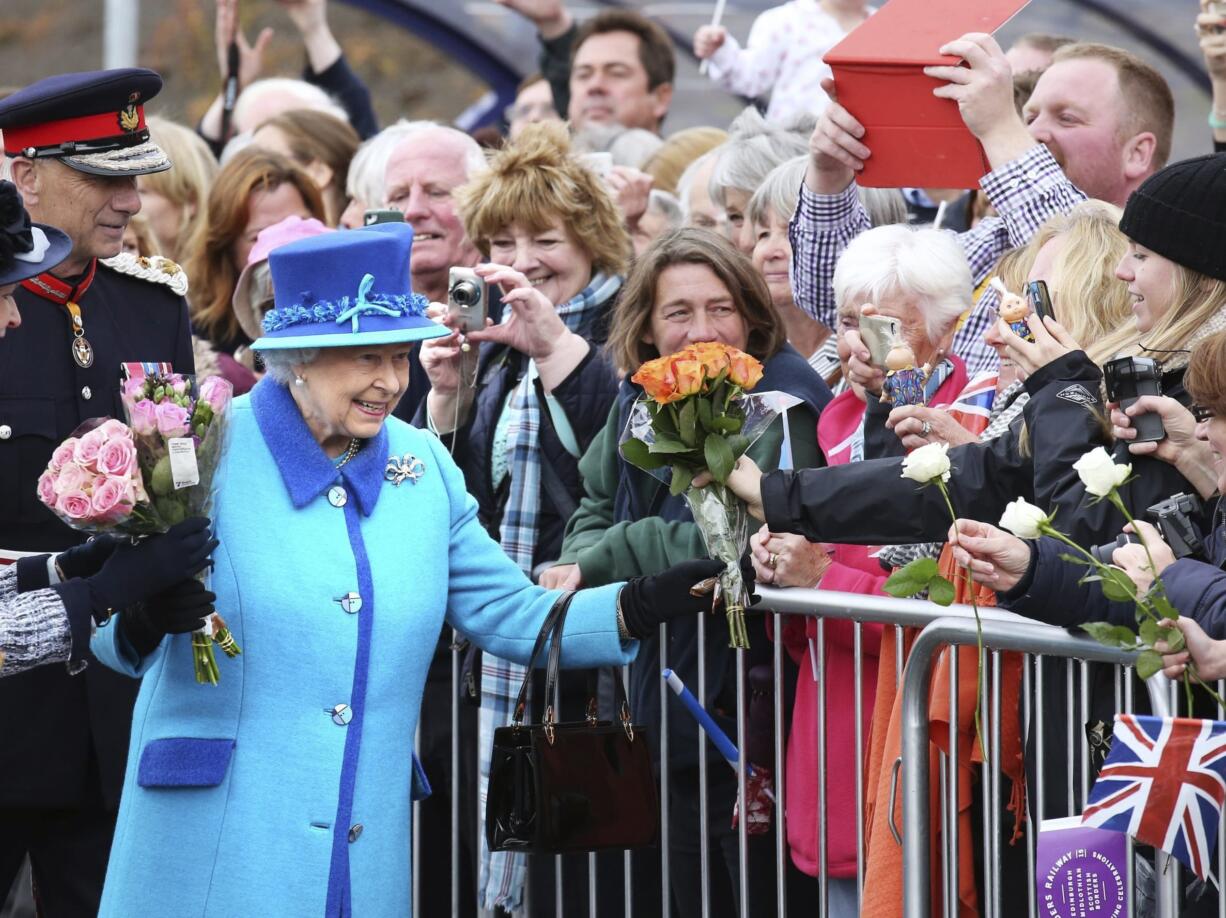 Britain's Queen Elizabeth II, on the day she becomes Britain's longest reigning monarch, accepts flowers from onlookers as she arrives to inaugurate the new multi million pound Scottish Borders Railway, at Tweedbank, Scotland, Wednesday Sept. 9, 2015.