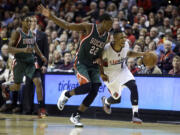 Portland Trail Blazers guard Damian Lillard, right, races downcourt against Milwaukee Bucks forward Khris Middleton during the second half of an NBA basketball game in Portland, Ore., Wednesday, Dec. 17, 2014. Lillard led the Trail Blazers in scoring with 29 points as they defeated the Bucks 104-97.