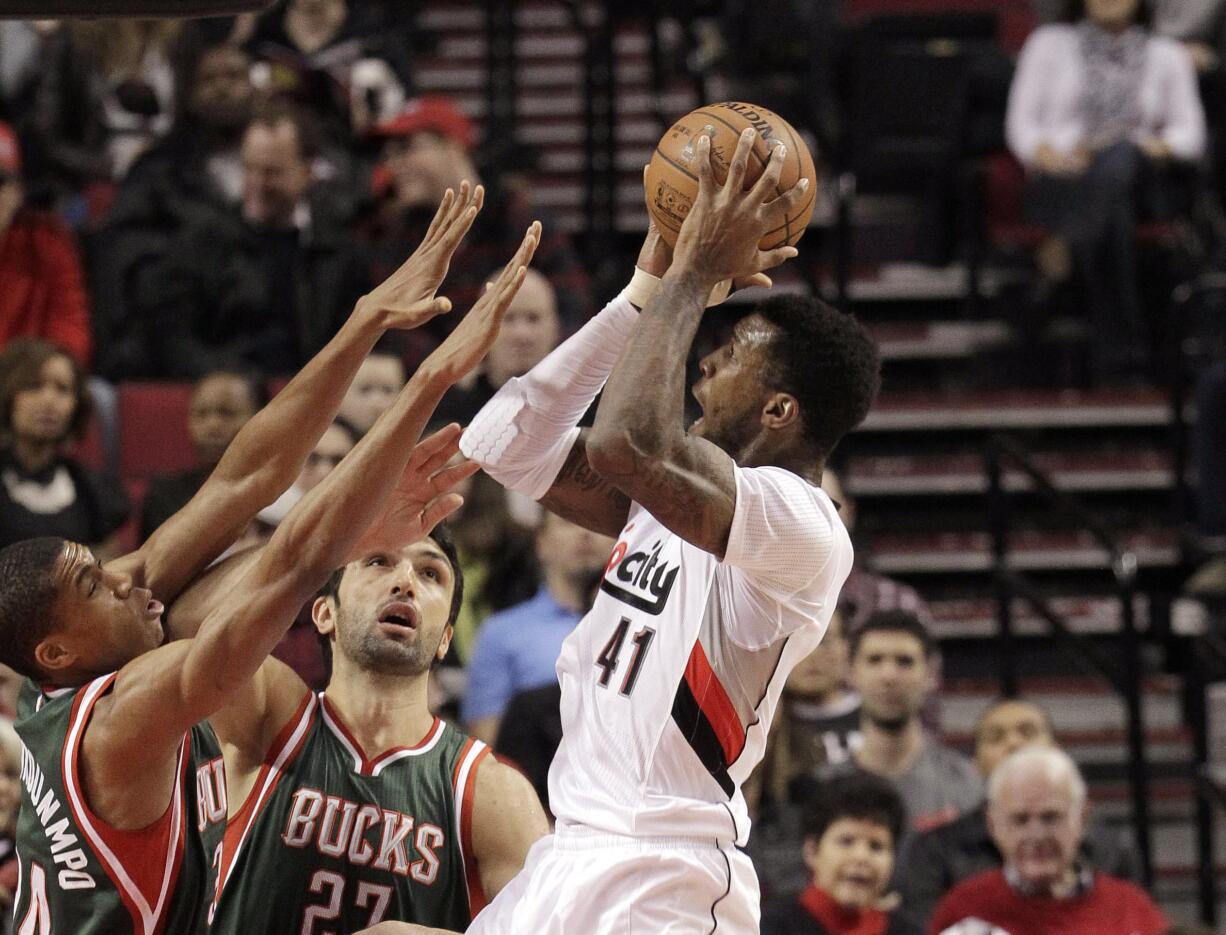 Portland Trail Blazers forward Thomas Robinson, right, shoots against Milwaukee Bucks forward Giannis Antetokounmpo and center Zaza Pachulia.