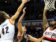 Milwaukee Bucks forward Ersan Ilyasova (7) drives to the basket on Portland Trail Blazers center Robin Lopez (42) and forward Dorell Wright (1) during the first half of an NBA basketball game in Portland, Ore., Tuesday, March 18, 2014.