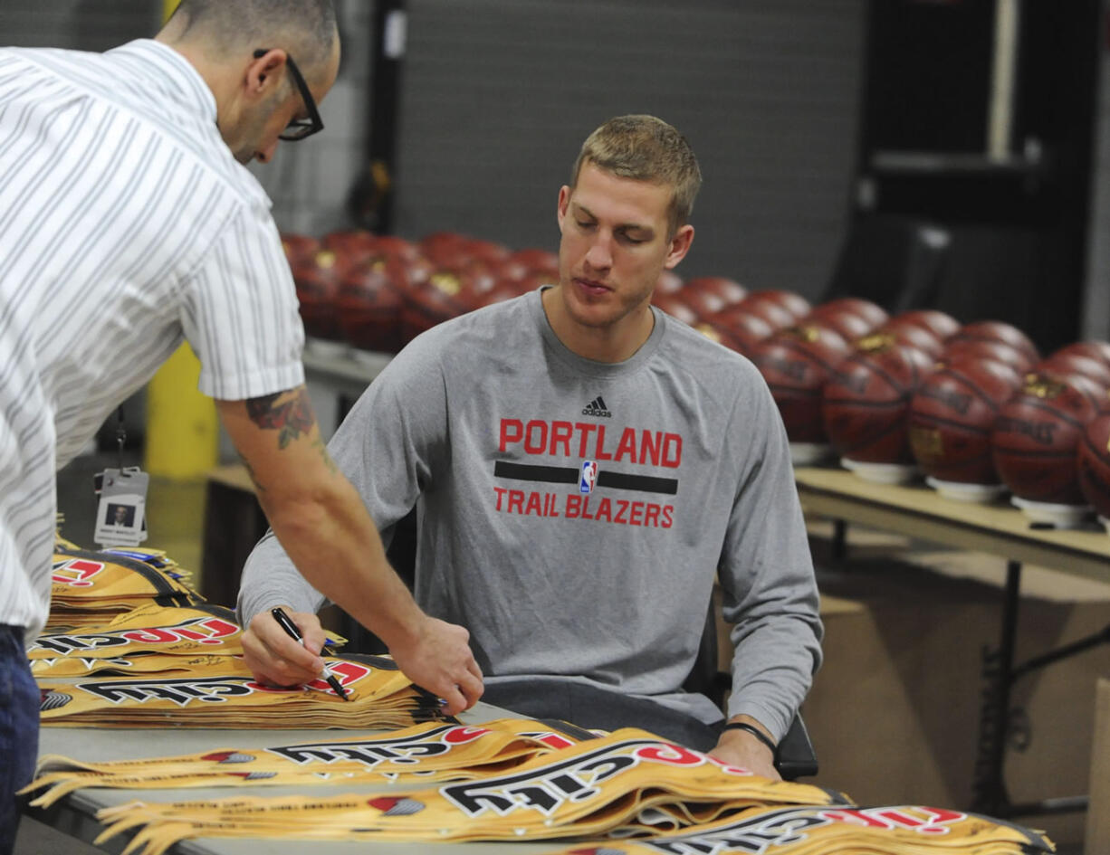 Portland Trail Blazers' Mason Plumlee, right, signs flags during the NBA basketball team media day, Monday, Sept. 28, 2015, in Portland, Ore.