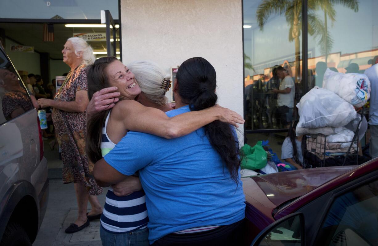 Homeless woman Jeanne Strickler, left, hugs her friends outside a laundromat before doing their laundry for free during a Laundry Love event on Aug. 13 in Huntington Beach, Calif. Laundry Love is a growing faith-driven movement that helps people change their lives by letting them change into clean clothes.