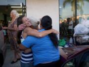 Homeless woman Jeanne Strickler, left, hugs her friends outside a laundromat before doing their laundry for free during a Laundry Love event on Aug. 13 in Huntington Beach, Calif. Laundry Love is a growing faith-driven movement that helps people change their lives by letting them change into clean clothes.