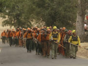 A California Department of Corrections and Rehabilitation inmate work crew walks through Sheep Ranch, Calif., on the way to battle a fire Sunday. Two of California's fastest-burning wildfires in decades overtook several Northern California towns, destroying homes and sending residents fleeing.