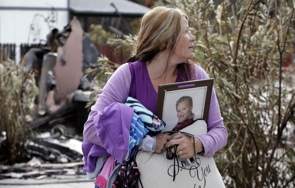 Sabrina Jose takes a last look back at her home after collecting some of her possessions during a brief, escorted visit, Wednesday, Sept. 16, 2015, in Middletown, Calif. Jose's still-standing home was surrounded by the remains of houses burned to the ground in a wildfire days earlier. Aided by drought, the flames have consumed more than 109 square since the fire sped Saturday through rural Lake County, less than 100 miles north of San Francisco.