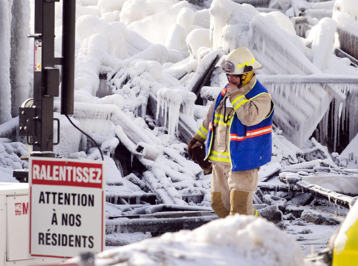 An emergency worker walks past a sign that reads &quot;Look out for our residents&quot; as he searchs the icy rubble of a fire that destroyed a seniors residence Thursday in L'Isle-Verte, Quebec.