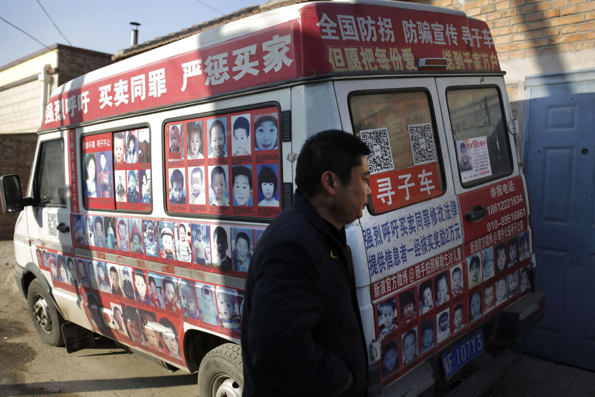 Xiao Chaohua walks past his van displaying photos of the missing children across China, which created by him to seek public attention to locate the children, parked outside his house in Beijing, China.