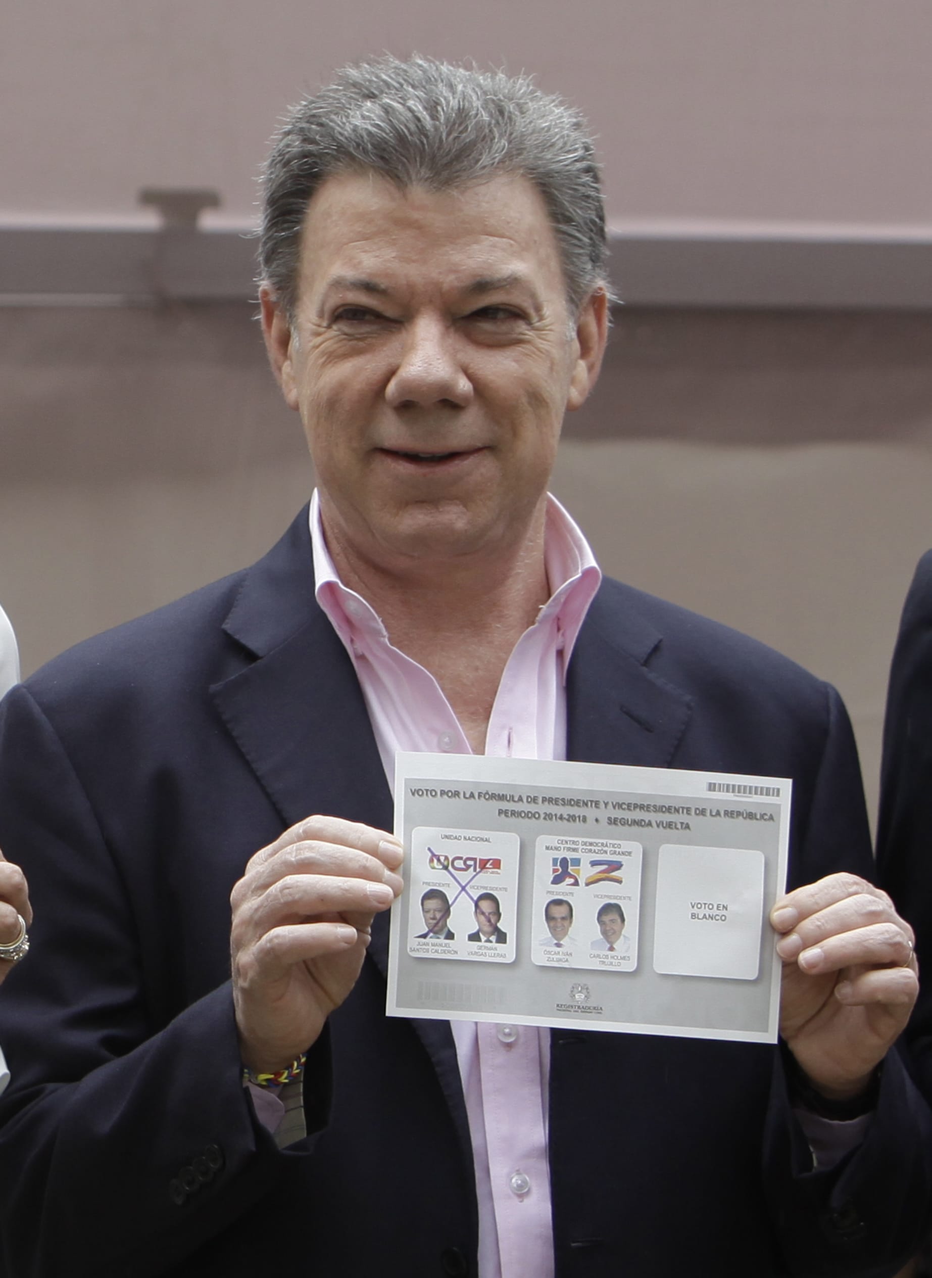 President Juan Manuel Santos shows his ballot before votiing during presidential elections in Bogota, Colombia, Sunday, June 15, 2014. Santos is seeking a second four-year term as candidate for the Social Party of National Unity.