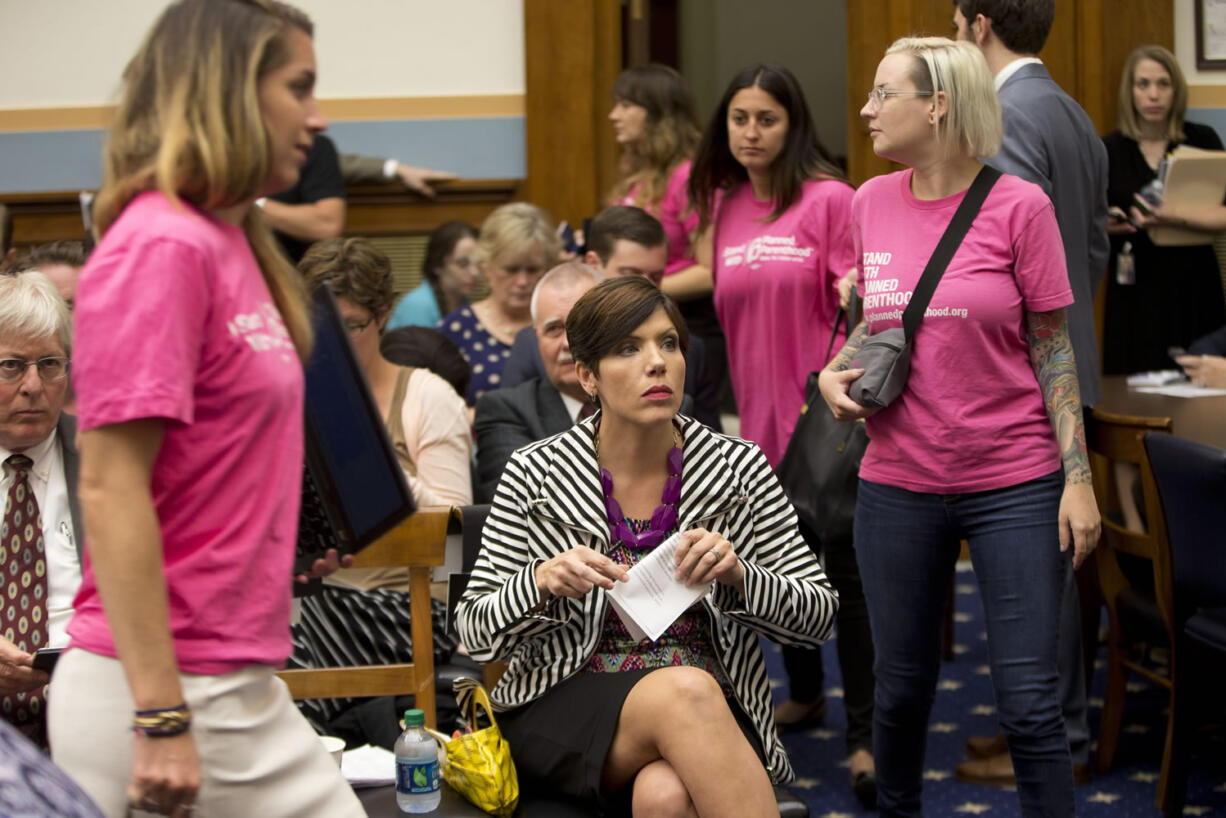 As supporters of Planned Parenthood looks for seats, Melissa Ohden, center, pro-life supporter from Gladstone, Mo., waits to testify before the House Judiciary Committee hearing at the Capitol in Washington examining the abortion practices of Planned Parenthood on Wednesday.