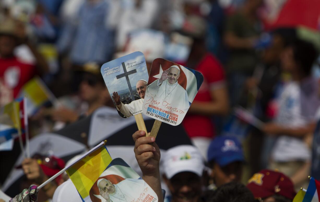 A person holds up hand fans promoting the papal visit in a crowd waiting for the arrival of Pope Francis at the Plaza of the Revolution where he will celebrate Mass, in Holguin, Cuba, on Monday. Holguin's plaza was packed with people waving flags and armed with umbrellas to protect themselves from the heat. Francis is the first pope to visit Holguin, Cuba's third-largest city.