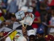 A person holds up hand fans promoting the papal visit in a crowd waiting for the arrival of Pope Francis at the Plaza of the Revolution where he will celebrate Mass, in Holguin, Cuba, on Monday. Holguin's plaza was packed with people waving flags and armed with umbrellas to protect themselves from the heat. Francis is the first pope to visit Holguin, Cuba's third-largest city.