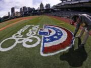 In this photo taken with a fisheye lens, Matt Gearhardt of the PNC ground crew paints the opening series logo on the field Sunday, March 30, 2014, in preparation for the Pittsburgh Pirates season opening baseball game, Monday, March 31 against the Chicago Cubs in Pittsburgh. (AP Photo/Gene J.