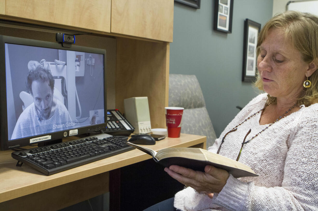 Nebraska Medical Center
Debbie Sacra reads Bible verses to her husband, Dr. Rick Sacra, via video link Wednesday at the Nebraska Medical Center in Omaha, Neb.