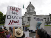 A small group of demonstrators stand on the steps of the Temple of Justice and in view of the Legislative Building on Wednesday in Olympia as they advocate for more state spending on education prior to a hearing before the state Supreme Court.