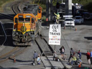 Abby Brockway waves from atop a tripod erected on train tracks to a pair of engines passing on an adjacent track Tuesday in Everett.