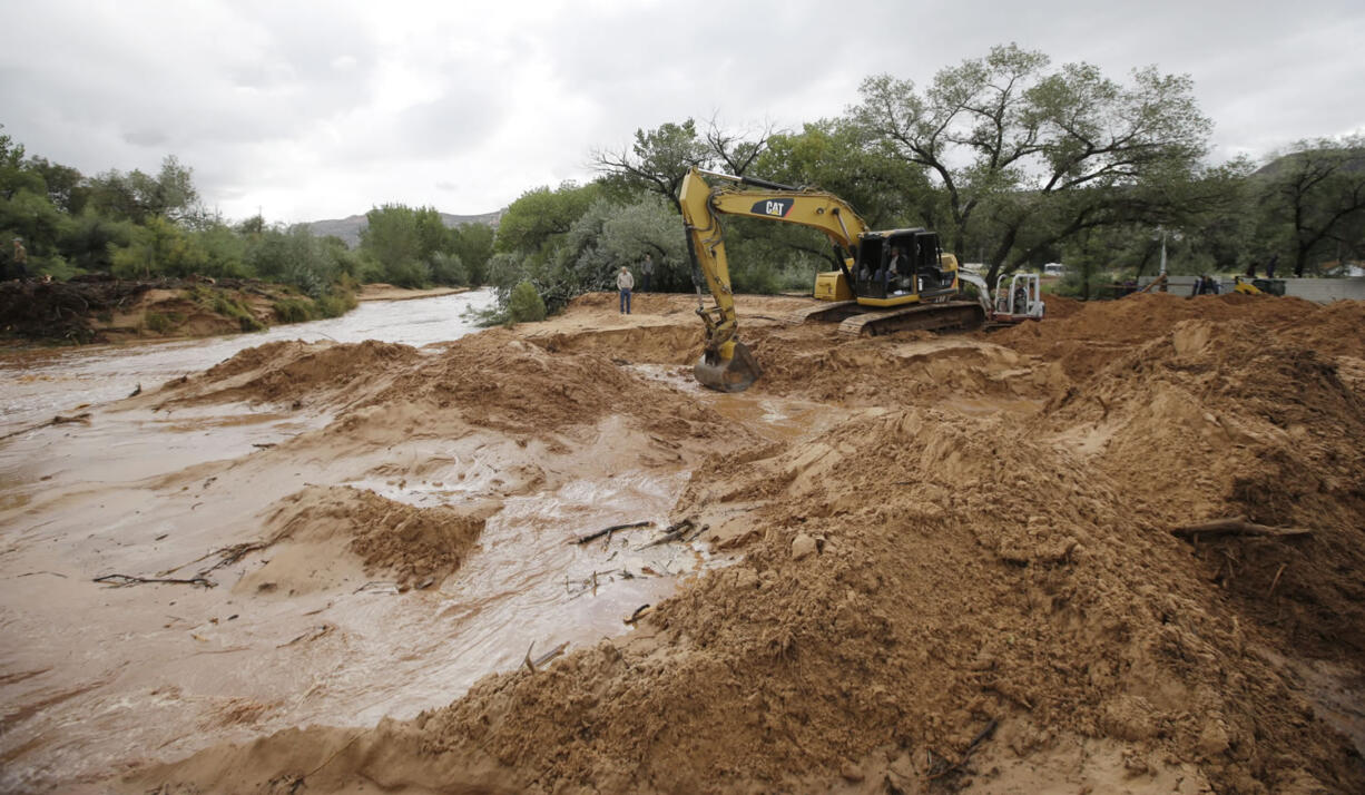 Crews clear mud and debris from a road following a flash flood Tuesday in Colorado City, Ariz. A wall of water swept away two vehicles carrying women and children in a Utah-Arizona border town Monday, killing at least eight people and leaving five others missing. Crews worked Tuesday morning to clear thousands of tons of mud and debris from the sister towns of Hildale, Utah, and Colorado City, Arizona.