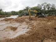 Crews clear mud and debris from a road following a flash flood Tuesday in Colorado City, Ariz. A wall of water swept away two vehicles carrying women and children in a Utah-Arizona border town Monday, killing at least eight people and leaving five others missing. Crews worked Tuesday morning to clear thousands of tons of mud and debris from the sister towns of Hildale, Utah, and Colorado City, Arizona.