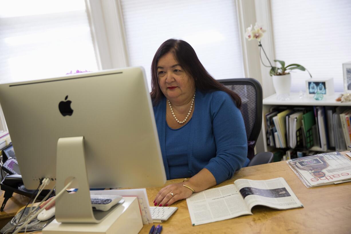 Jane Delgado, president of the National Alliance for Hispanic Health, works in her office March 24, 2014 in Washington. A change in government procedures has led to a big jump in people losing coverage under the Obama health care law because of immigration and citizenship issues.