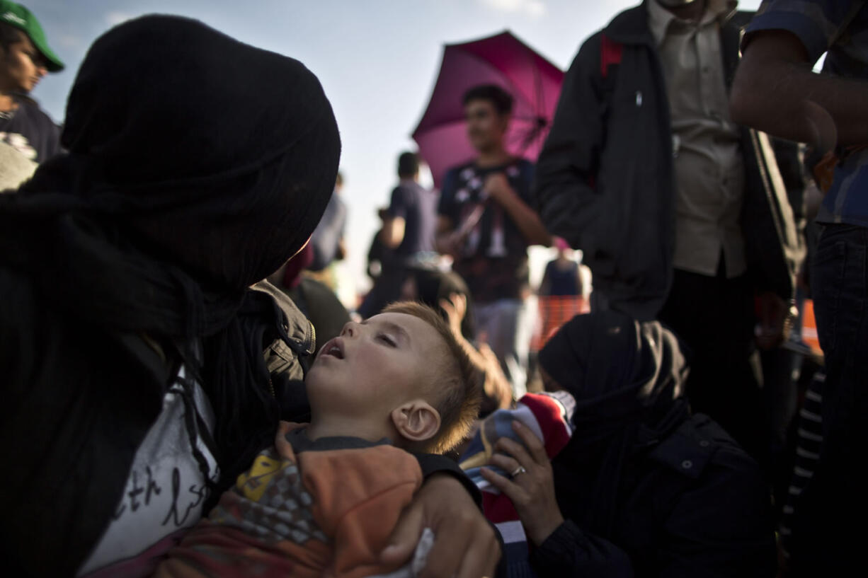 A Syrian child sleeps on his mother's lap as they wait Sunday with others to board a bus that will take them to the center for asylum seekers, after crossing the Serbian-Hungarian border near Roszke, southern Hungary. At least four countries Friday firmly rejected a European Union plan to impose refugee quotas to ease a worsening migrant crisis that Germany's foreign minister said was "probably the biggest challenge" in the history of the 28-nation bloc.