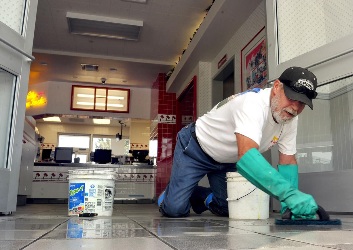 Gary McChesney finishes-up the floor tiles on the entrance to Medford's In-N-Out restaurant Aug. 26 in Medford, Ore.