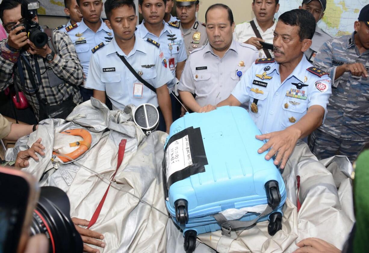 Commander of 1st Indonesian Air Force Operational Command Rear Marshall Dwi Putranto, right, shows airplane parts and a suitcase found floating on the water near the site where AirAsia Flight 8501 disappeared, during a press conference at the airbase in Pangkalan Bun, Central Borneo, Indonesia, Tuesday, Dec. 30, 2014. Bodies and debris seen floating in Indonesian waters Tuesday, painfully ended the mystery of AirAsia Flight 8501, which crashed into the Java Sea and was lost to searchers for more than two days. The writings on the suitcase reads &quot;Recovered by KRI Bung Tomo.&quot;  KRI Bung Tomo is the name of an Indonesian Navy ship. The numbers on the suitcase are the coordinates.