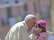 Pope Francis kisses a girl in front the Duomo of Cassano allo Jonio, southern Italy, on Saturday.