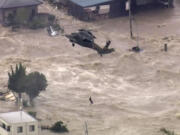 In this photo taken from video provided by Japan's Tokyo Broadcasting System television network, a man, who was stranded in the middle of raging floodwaters, is rescued by a military helicopter in Joso, Ibaraki prefecture Thursday. Raging floodwaters broke through a berm Thursday and swamped the city near Tokyo, washing away houses, forcing dozens of people to rooftops to await helicopter rescues and leaving one man clinging for his life to a utility pole.