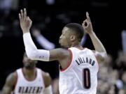 Portland Trail Blazers guard Damian Lillard signals after sinking a three  point shot during the second half of an NBA basketball game against the Utah Jazz in Portland, Ore., Friday, Feb. 21, 2014.  Lillard led Portland in scoring with 28 points as they won 102-94.