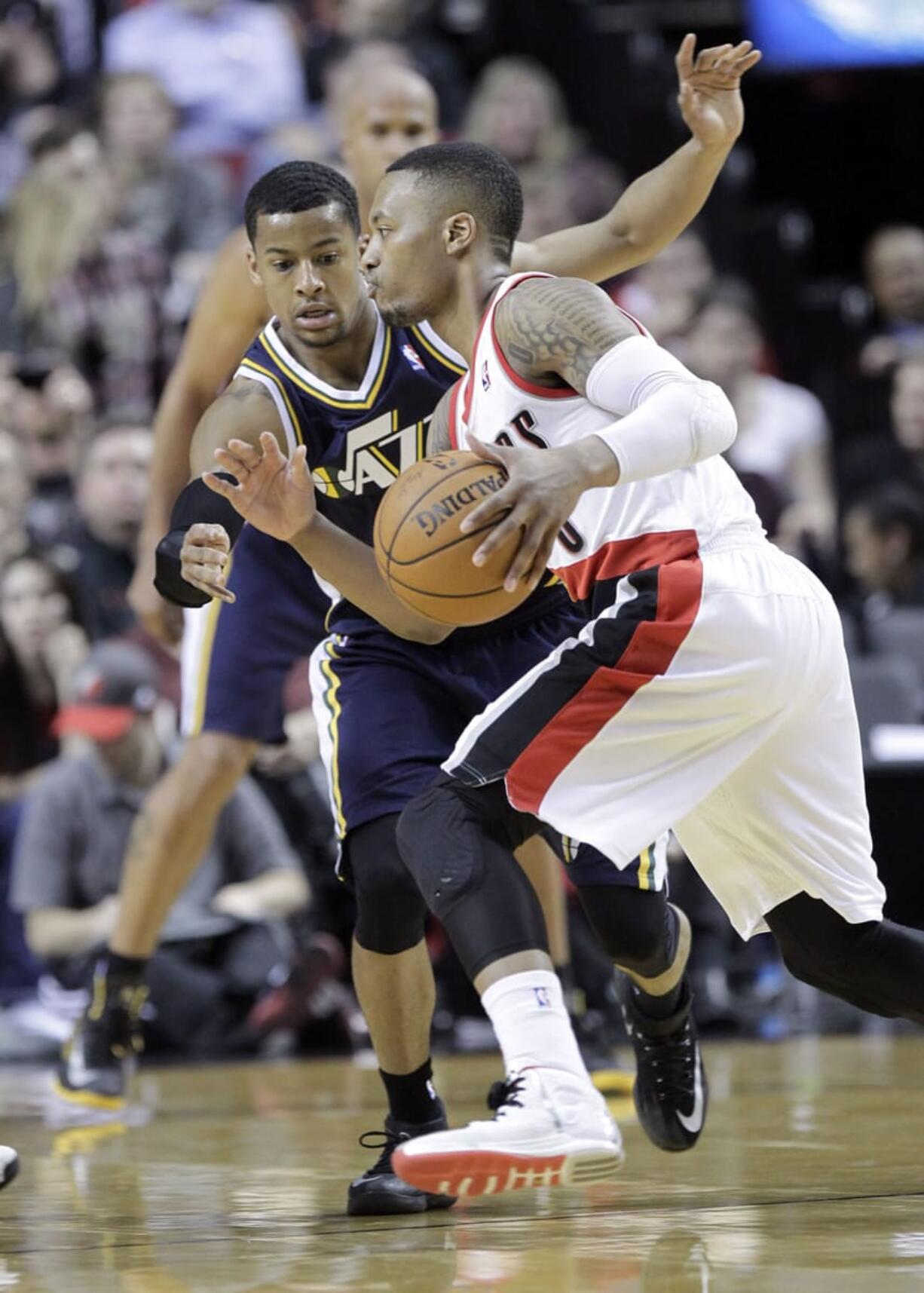 Portland Trail Blazers guard Damian Lillard, right, drives on Utah Jazz guard Trey Burke during the second half Friday. Lillard led Portland in scoring with 28 points as the Blazers won 102-94.