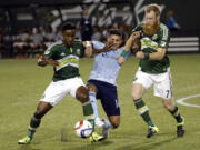 Sporting Kansas City forward Dom Dwyer, middle, battles for the ball with Portland Timbers midfielder George Fochive, left, and defender Nat Borchers during the first half of an MLS soccer match in Portland, Ore., Wednesday, Sept. 9, 2015.