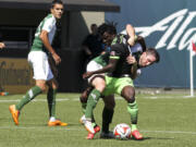 Seattle Sounders player Obafemi Martins, front, vies for the ball against Portland Timbers' Danny O'Rourke Sunday in Portland.