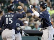 Seattle Mariners' Justin Smoak (17) is welcomed home by teammate Kyle Seager (15) on a two-run home run against the Houston Astros in the seventh inning of a baseball game on Saturday, May 3, 2014, in Houston.