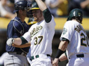 Oakland Athletics' Brandon Moss (37) is congratulated by Josh Donaldson, right, after Moss hit a three-run home run off Seattle Mariners' Erasmo Ramirez in the third inning of a baseball game Sunday, April 6, 2014, in Oakland, Calif.