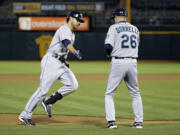 Seattle Mariners' Stefen Romero, left, shakes hands with third base coach Rich Donnelly after Romero's solo home run against the Oakland Athletics during the fifth inning of a baseball game on Monday, May 5, 2014, in Oakland, Calif.