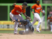 Miami Marlins second baseman Donovan Solano (17) tags Seattle Mariners runner Robinson Cano (22) out, stealing at second on eighth inning of a baseball game in Miami, Sunday, April 20,2014. The Marlins won 3-2.