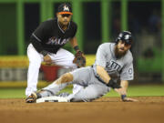 After tagging out Seattle Mariners' Dustin Ackley, right, Miami Marlins' Donovan Solano looks to first base as he turns the double play in the sixth inning Saturday.