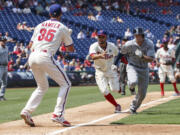 Philadelphia Phillies third baseman Andres Blanco, center, throws the ball to starting pitcher Cole Hamels, left, as they catch Seattle Mariners' Chris Denorfia, right, stealing during the fourth inning of a baseball game, Wednesday, Aug. 20, 2014, in Philadelphia.