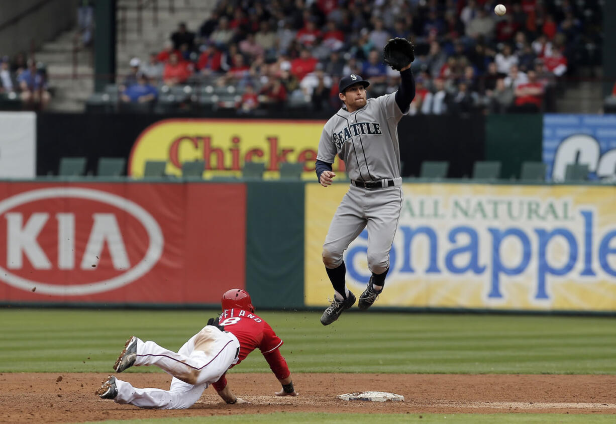 Texas Rangers Mitch Moreland (18) dives back to second as Seattle Mariners shortstop Brad Miller (5) has to leap in the air to catch the throw from catcher John Buck during the third inning Thursday, April 17, 2014, in Arlington, Texas. Moreland was safe on the play.