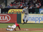 Texas Rangers Mitch Moreland (18) dives back to second as Seattle Mariners shortstop Brad Miller (5) has to leap in the air to catch the throw from catcher John Buck during the third inning Thursday, April 17, 2014, in Arlington, Texas. Moreland was safe on the play.