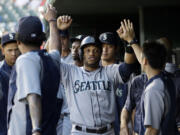 Seattle Mariners' Robinson Cano, center, is congratulated in the dugout after scoring on a Kyle Seager single in the second inning against the Texas Rangers, Thursday, Sept. 4, 2014, in Arlington, Texas.